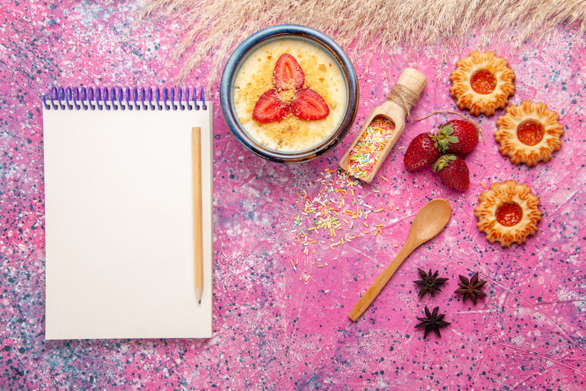 vue-de-dessus-delicieux-dessert-cremeux-avec-bloc-notes-de-fraises-tranchees-rouges-et-petits-biscuits-sur-fond-rose-clair-dessert-creme-glacee-aux-baies-creme-aux-fruits-sucres